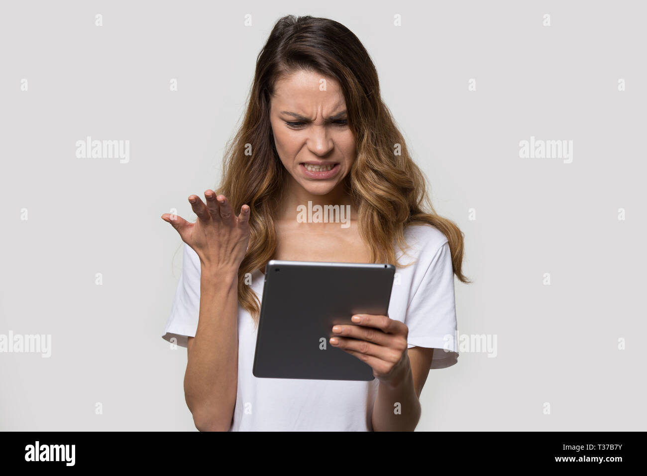 Gereizte Frau an Tablet Bildschirm schaut fühlt sich wütend Stockfoto