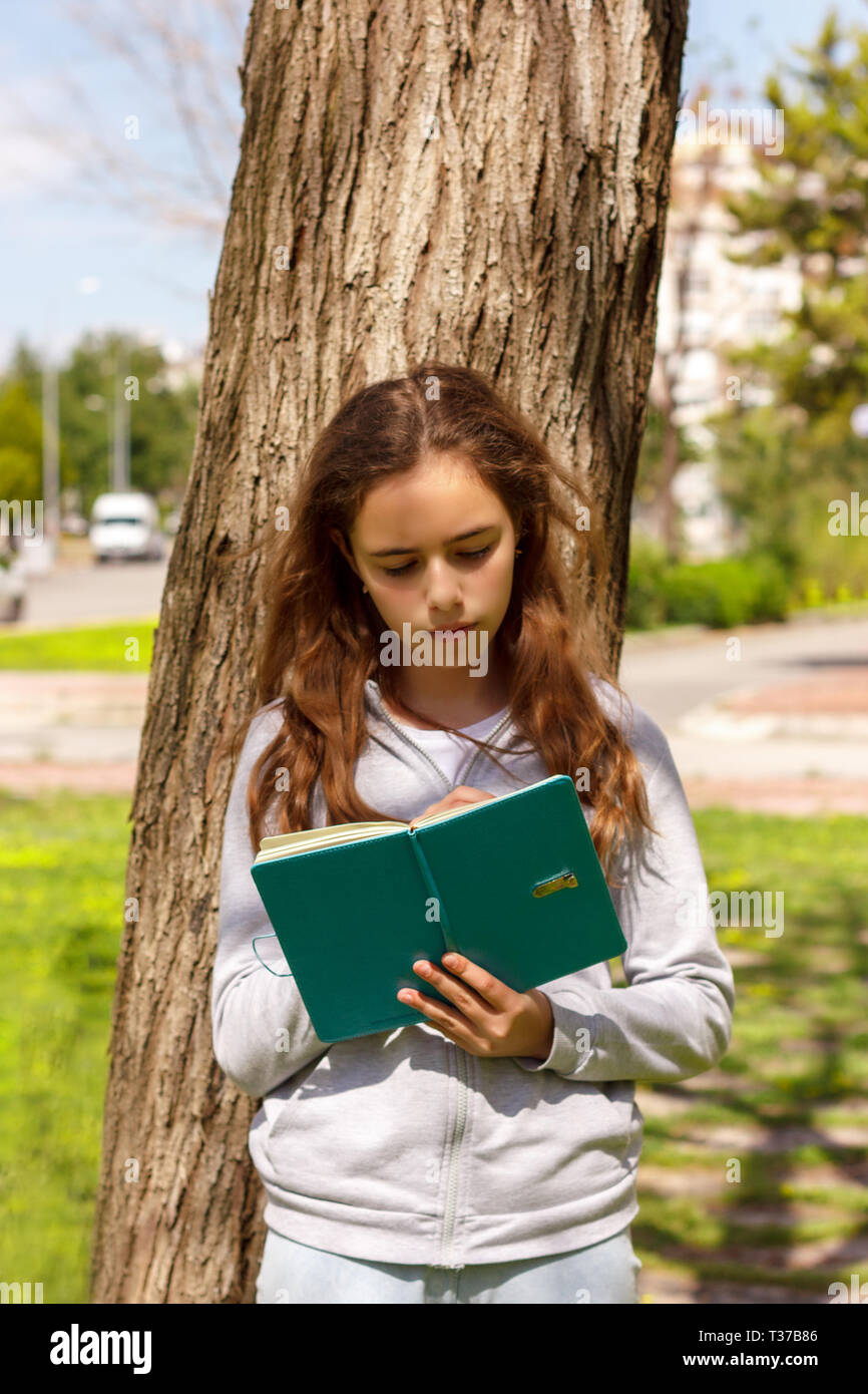 Cute Teen Girl lesen Buch von der Pine Tree Stockfoto