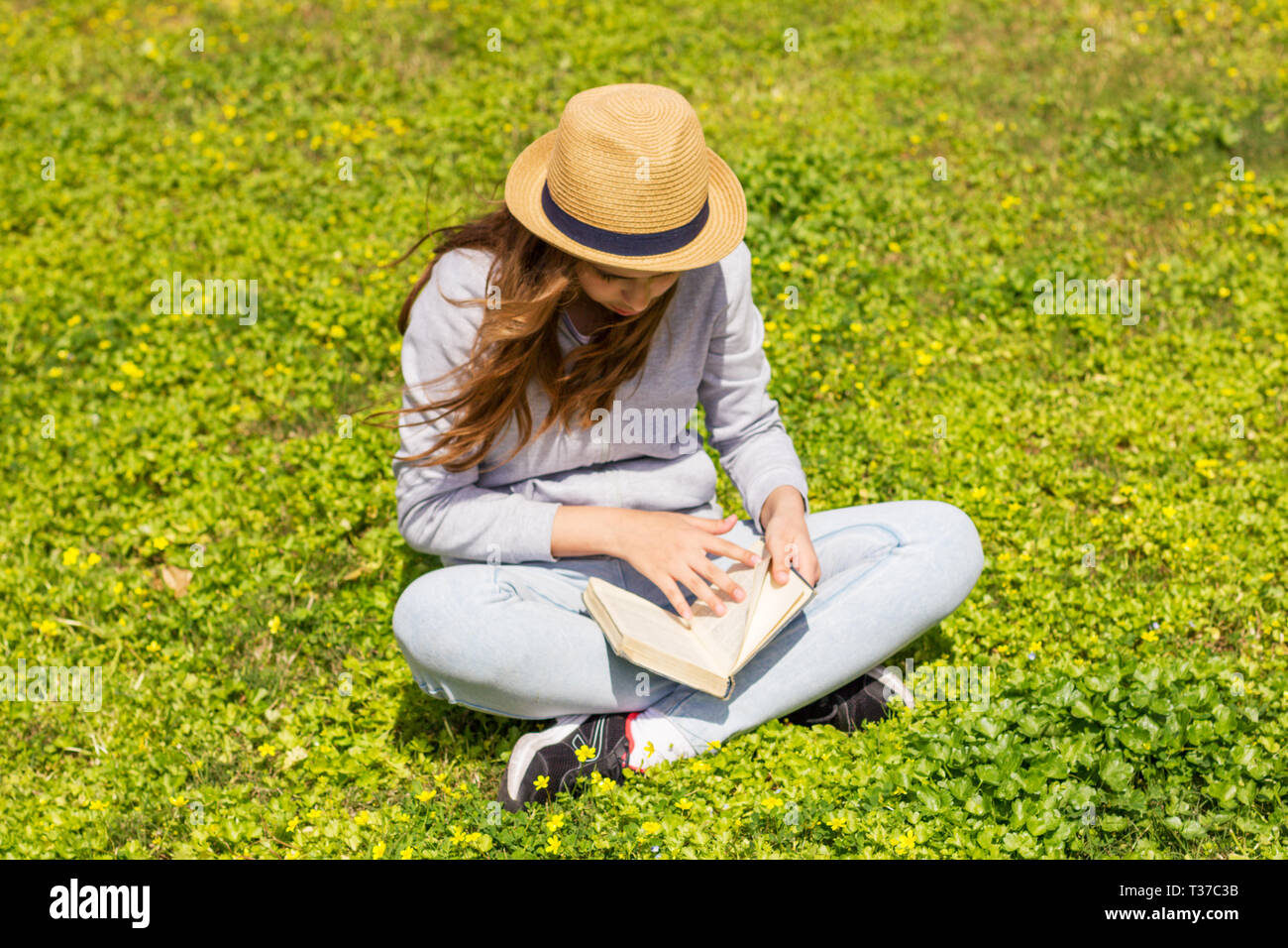 Cute teen Mädchen das Lesen eines Buches auf der grünen Wiese. Selektiver Fokus Stockfoto