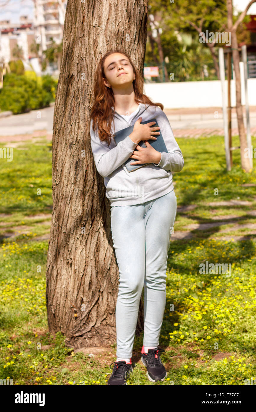 Cute teen Mädchen träumt von der Liebe in der Nähe von Pine Tree. Selektiver Fokus Stockfoto