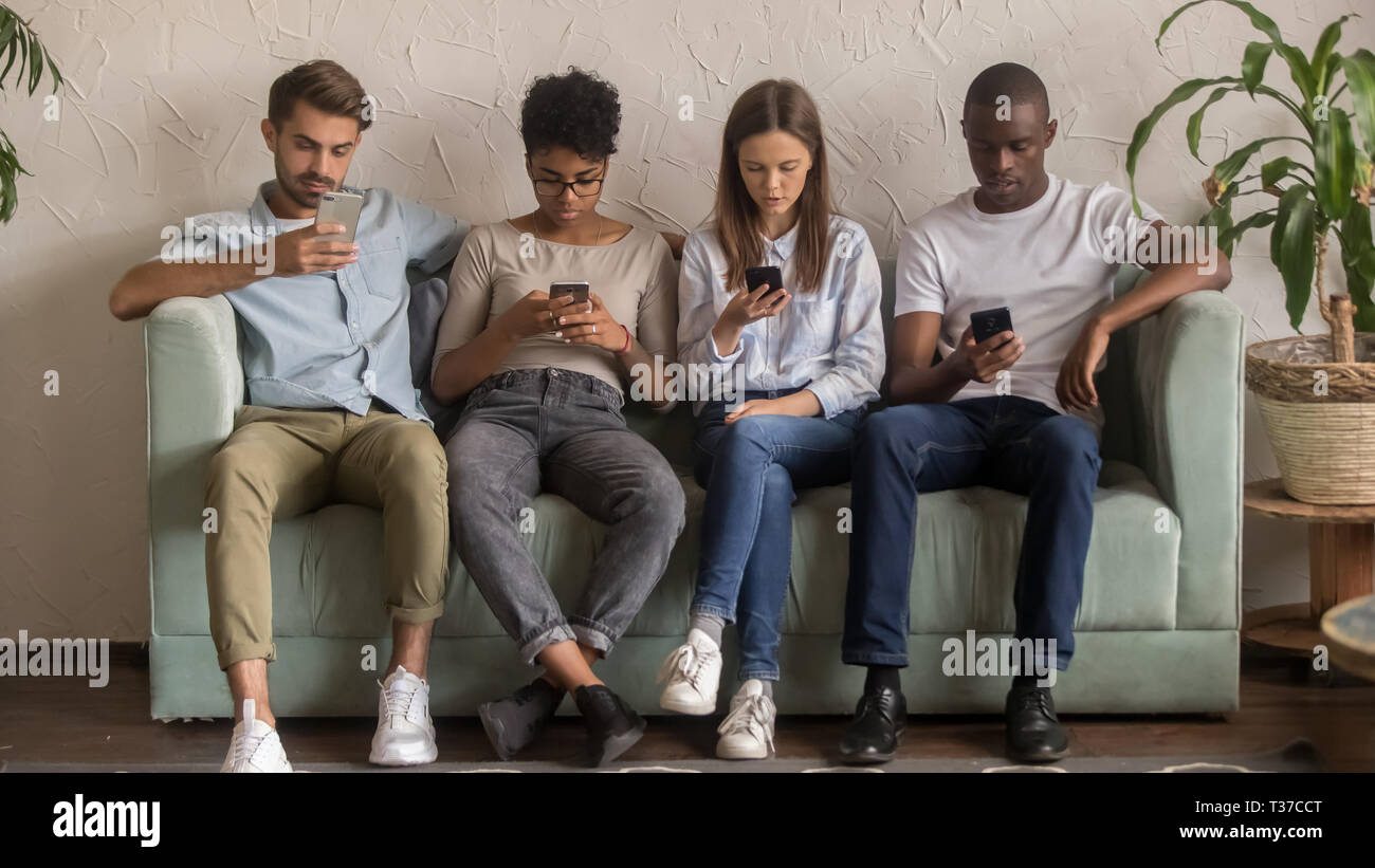 Multikulturelle Menschen mit Smartphones ignorieren einander Sitzen auf einem Sofa Stockfoto