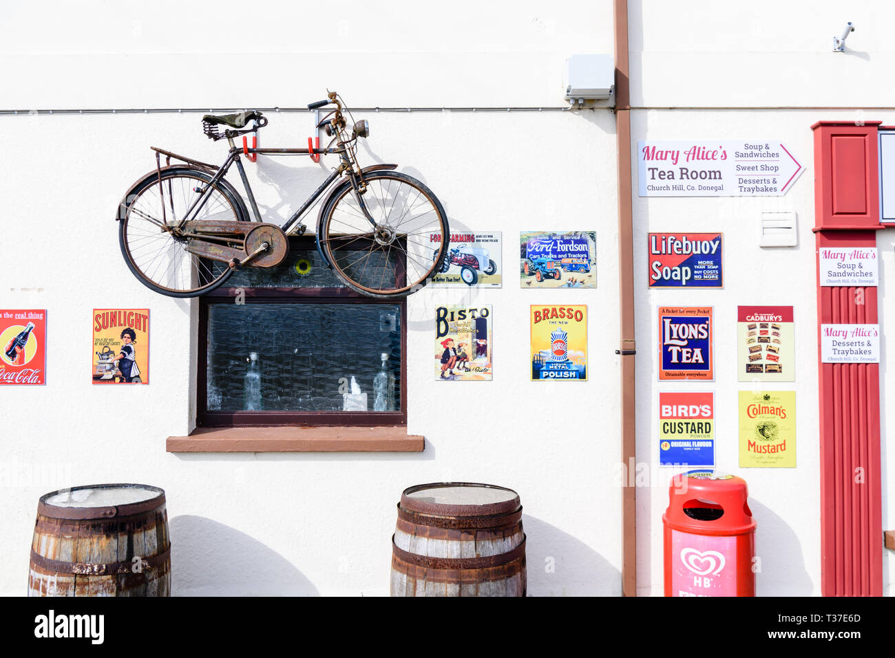 Ein Fahrrad- und ein altmodisches Metall werbeschilder an der Wand außerhalb eines Irish Shop. Stockfoto