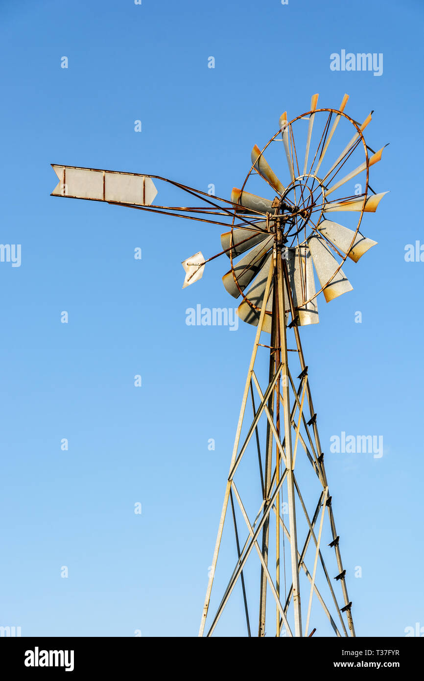 Low Angle View eines altmodischen, multi-Klinge, Metall wind Pumpe auf einem Gitterturm gegen den blauen Himmel. Stockfoto