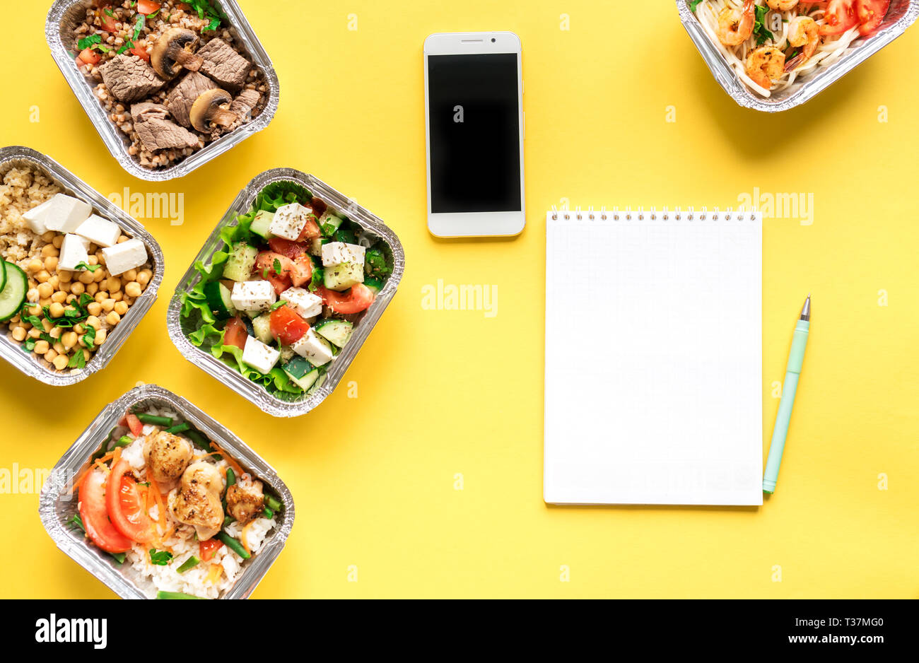 Gesunde Mahlzeiten in Folie Boxen und Smartphone auf Gelb, Ansicht von oben, flach. Gesundes Essen Lieferung Konzept. Fitness Ernährung Ernährung, kopieren. Stockfoto