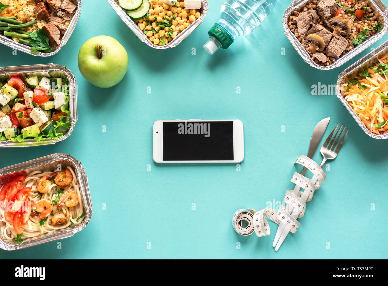Speisen im Smartphone mit gesunden Lebensmitteln. Fitness Ernährung für Ernährung. Täglichen Mahlzeiten in Kartons auf Blau, top anzeigen, kopieren. Stockfoto