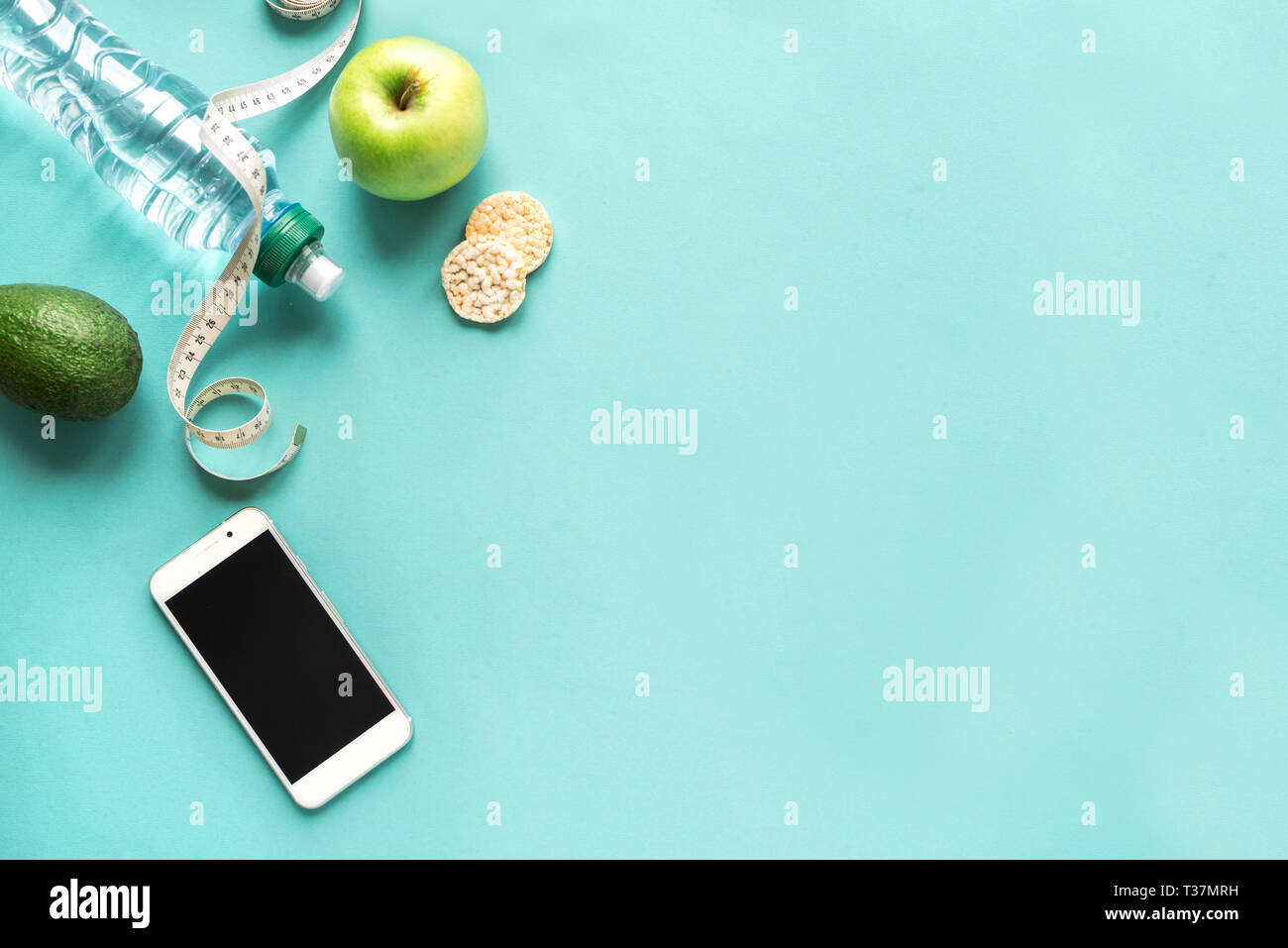 Mit Wasser, Obst und Maßband Smartphone. Fitness Ernährung Anwendung in Smartphone, Diät Konzept auf Blau, top anzeigen, kopieren. Stockfoto