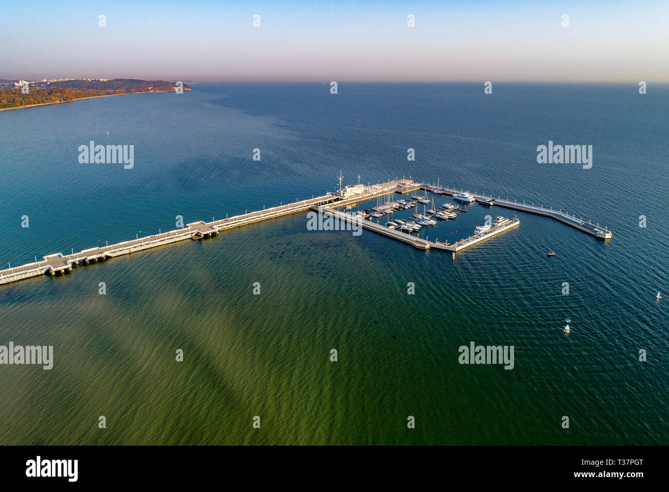 Polen, Sopot Resort. Hölzerne Seebrücke (Molo) mit Marina, Yachten, Segelboote und die Promenade. Far View von Gdynia in thw Hintergrund. Luftbild bei Sonnenaufgang Stockfoto