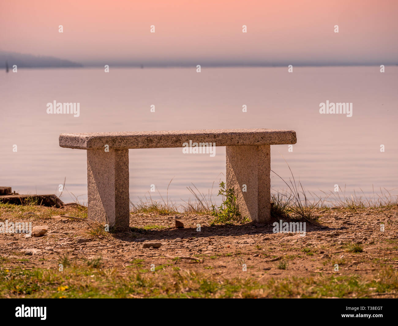 Bild mit Steinbank vor dem Lago Maggiore mit Blick auf den Sonnenuntergang Stockfoto