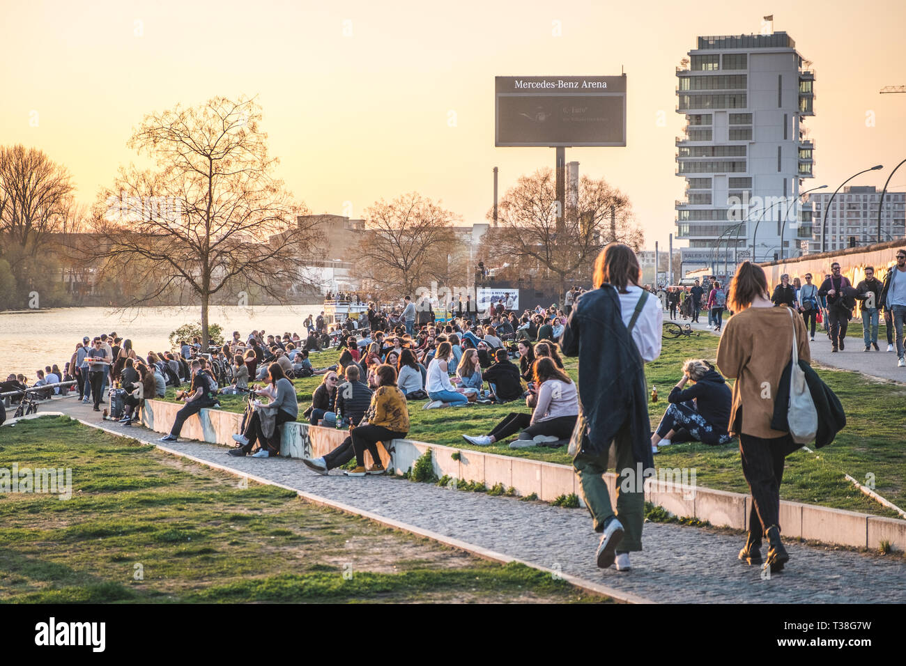 Berlin, Deutschland - April, 2019: die Menschen am Flußufer an der Berliner Mauer/East Side Gallery bei Sonnenuntergang in Berlin, Deutschland Stockfoto