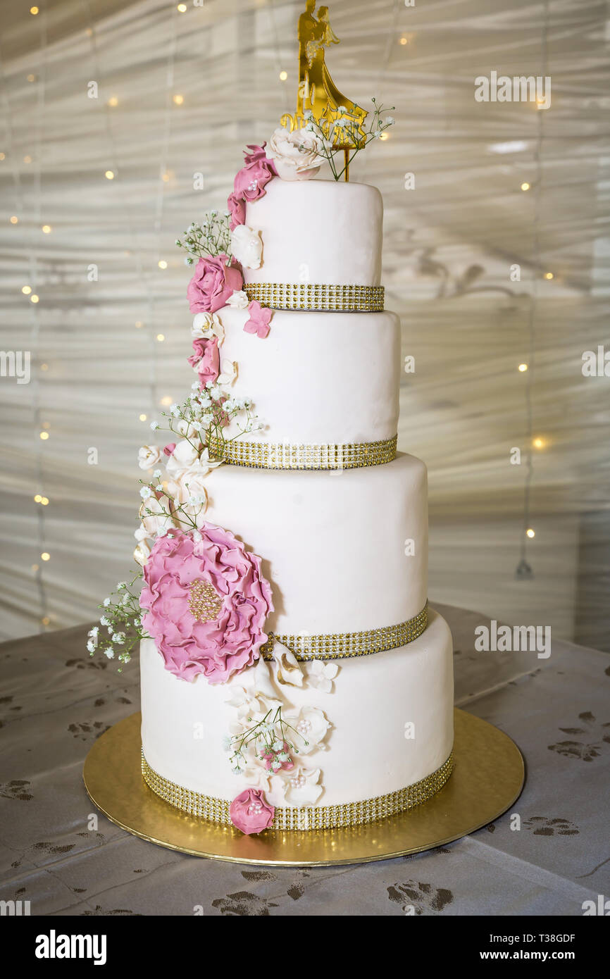 Hochzeitstorte mit weißen und rosa Zucker Blumen und gold Topper Stockfoto