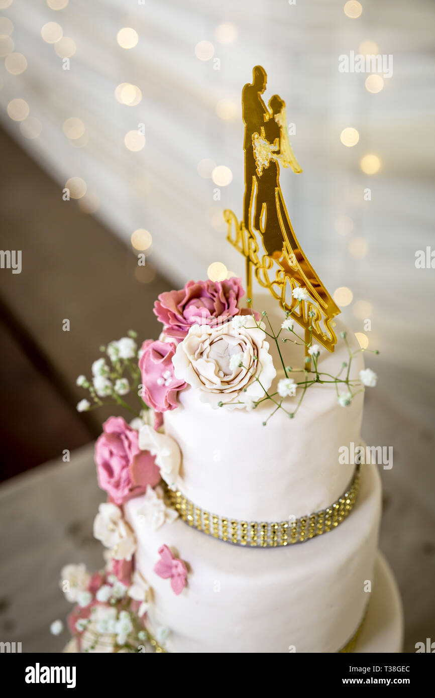 Hochzeitstorte mit weißen und rosa Zucker Blumen und gold Topper Stockfoto