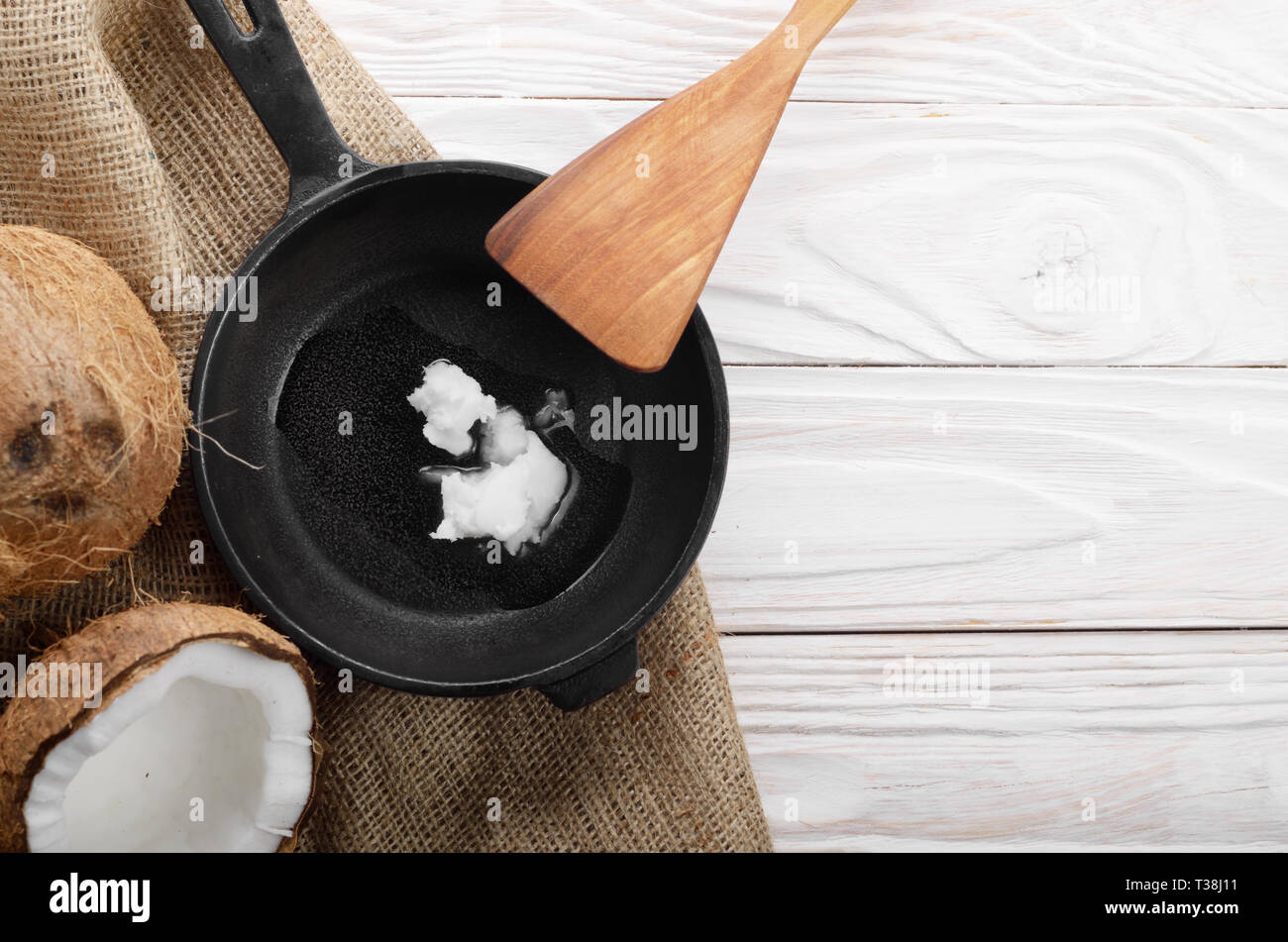 Kokosnuss, Shell mit Fleisch, Gusseisen Skillet und Spachtel auf Hanf Sack auf weißen Küche aus Holz Tisch Stockfoto