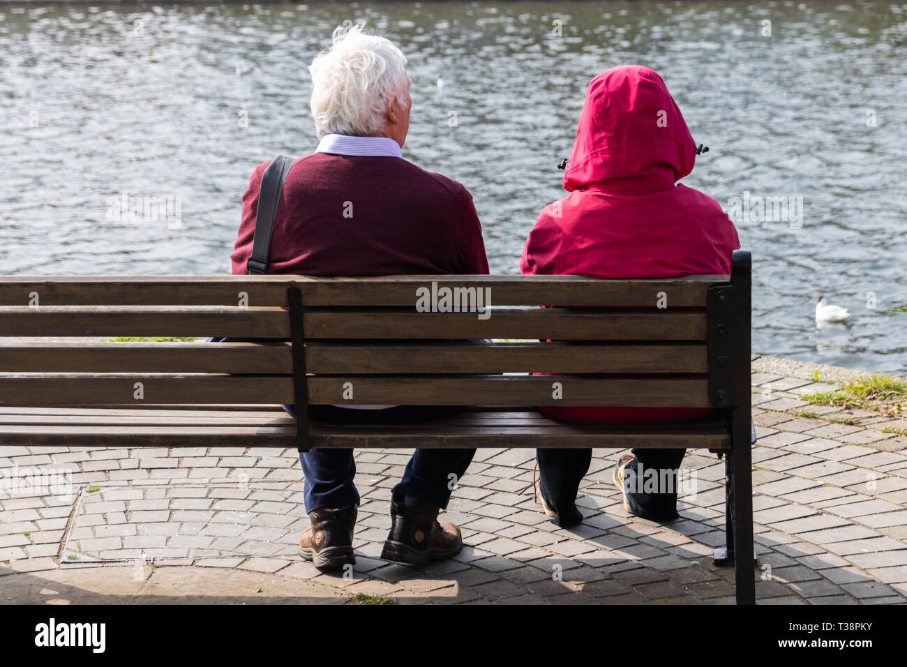 Ältere Paare setzte sich auf eine Holzbank mit Blick auf das Wasser Stockfoto
