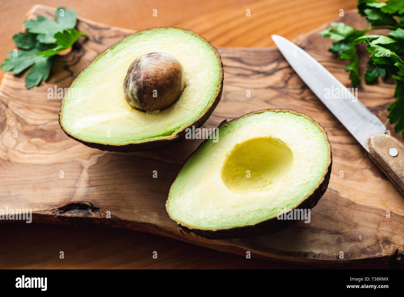 Zwei avocado Hälften auf Holz Schneidebrett, Detailansicht. Konzept der gesunde Nahrung, gesunde Ernährung Stockfoto
