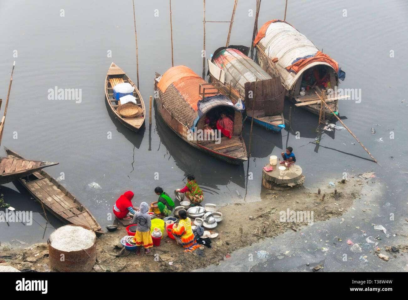 Hausboot und Frauen waschen Wäsche und Geschirr auf dem Fluss, Dhaka, Bangladesch Stockfoto