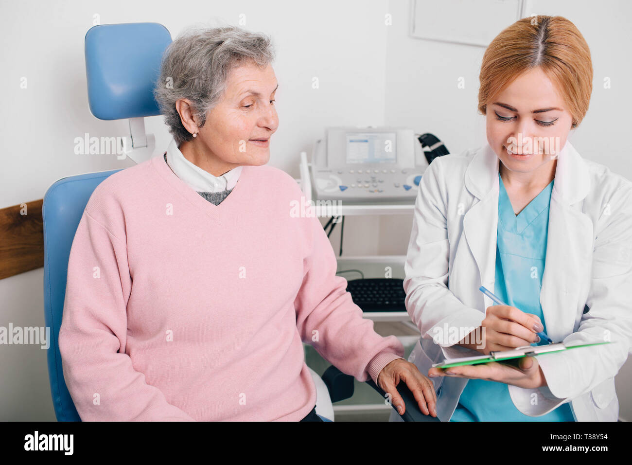 Ärztin zu erklären, im Alter von Patienten im Büro im Krankenhaus. Aufnehmen einer medizinischen Chart patien s Beschweren Stockfoto