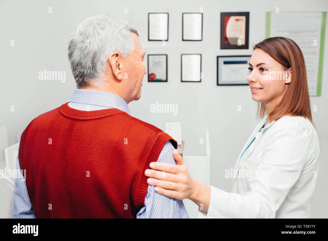 Arzt beruhigend älterer Patienten während einer Untersuchung an der Klinik Stockfoto