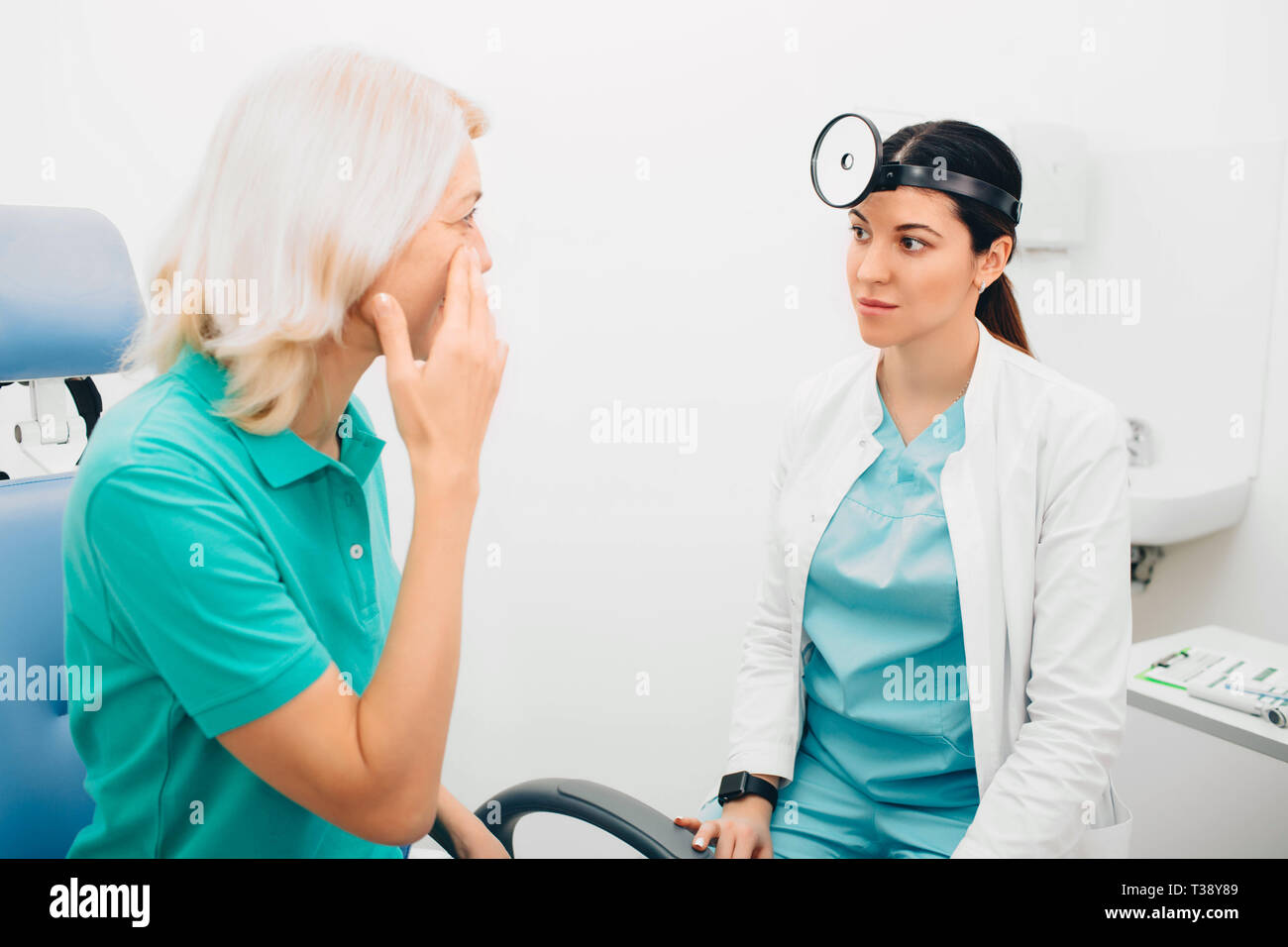 Der Arzt hört den Beschwerden des Patienten zu, während der Patient auf die Kieferhöhlen zeigt. Sinusitis, Symptome. Stockfoto