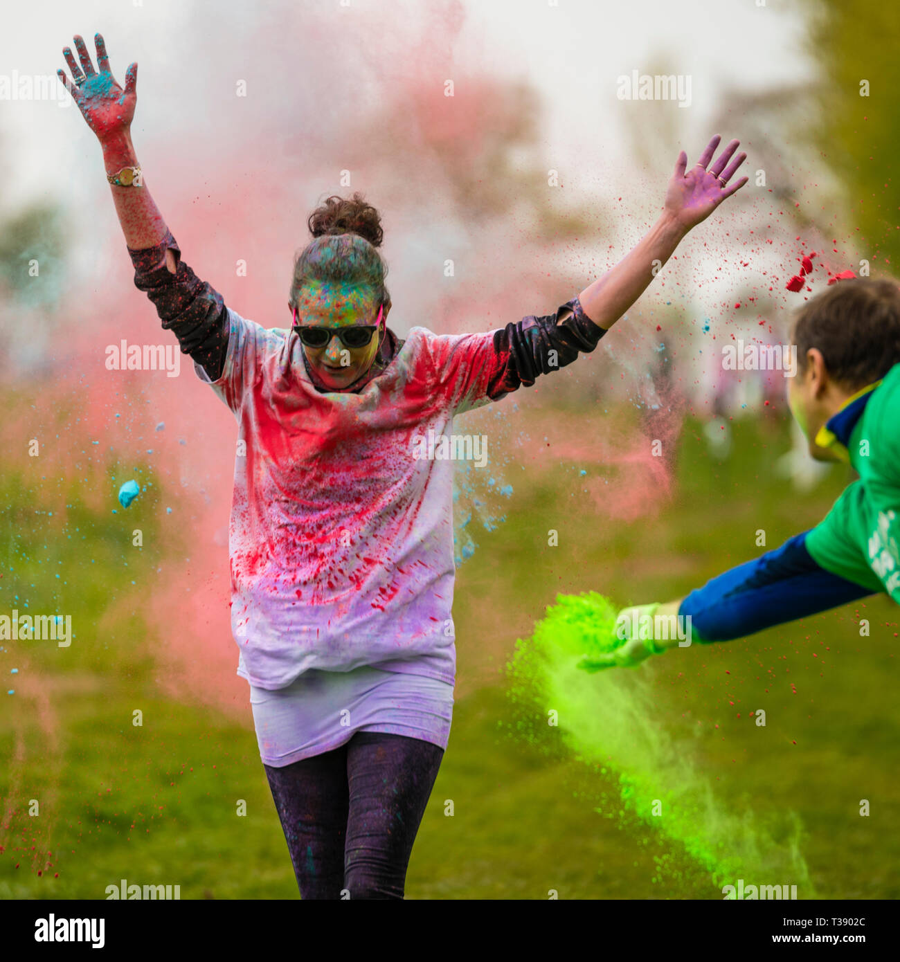 Nach Läuferin mit Armen in Farbe auf Macmillan Cancer Charity 5K Farbe Fun Run wird abgedeckt. Stockfoto