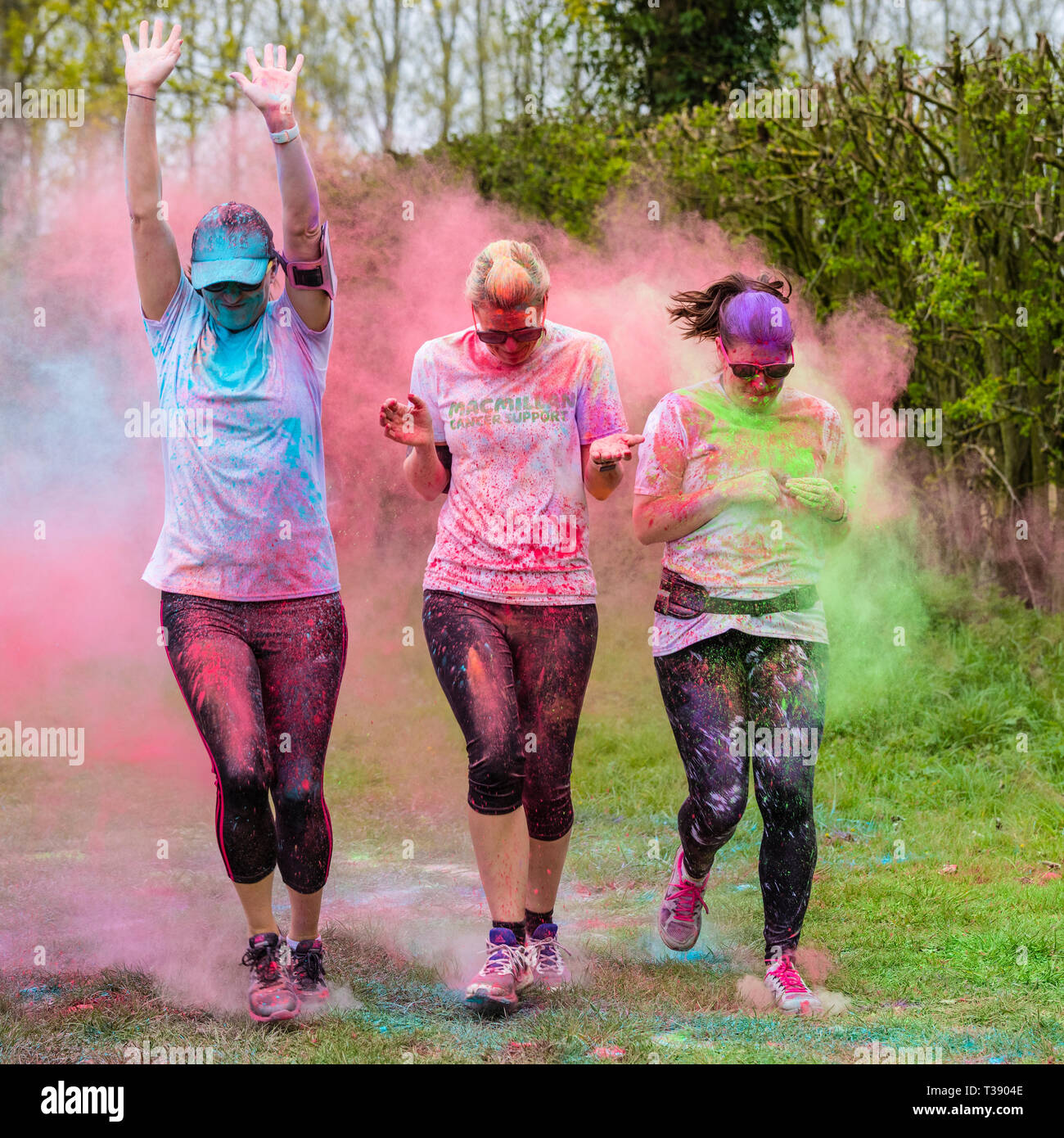 Drei Frauen Läufer in Farbe auf Macmillan Cancer Charity 5K Farbe Fun Run abgedeckt. Stockfoto