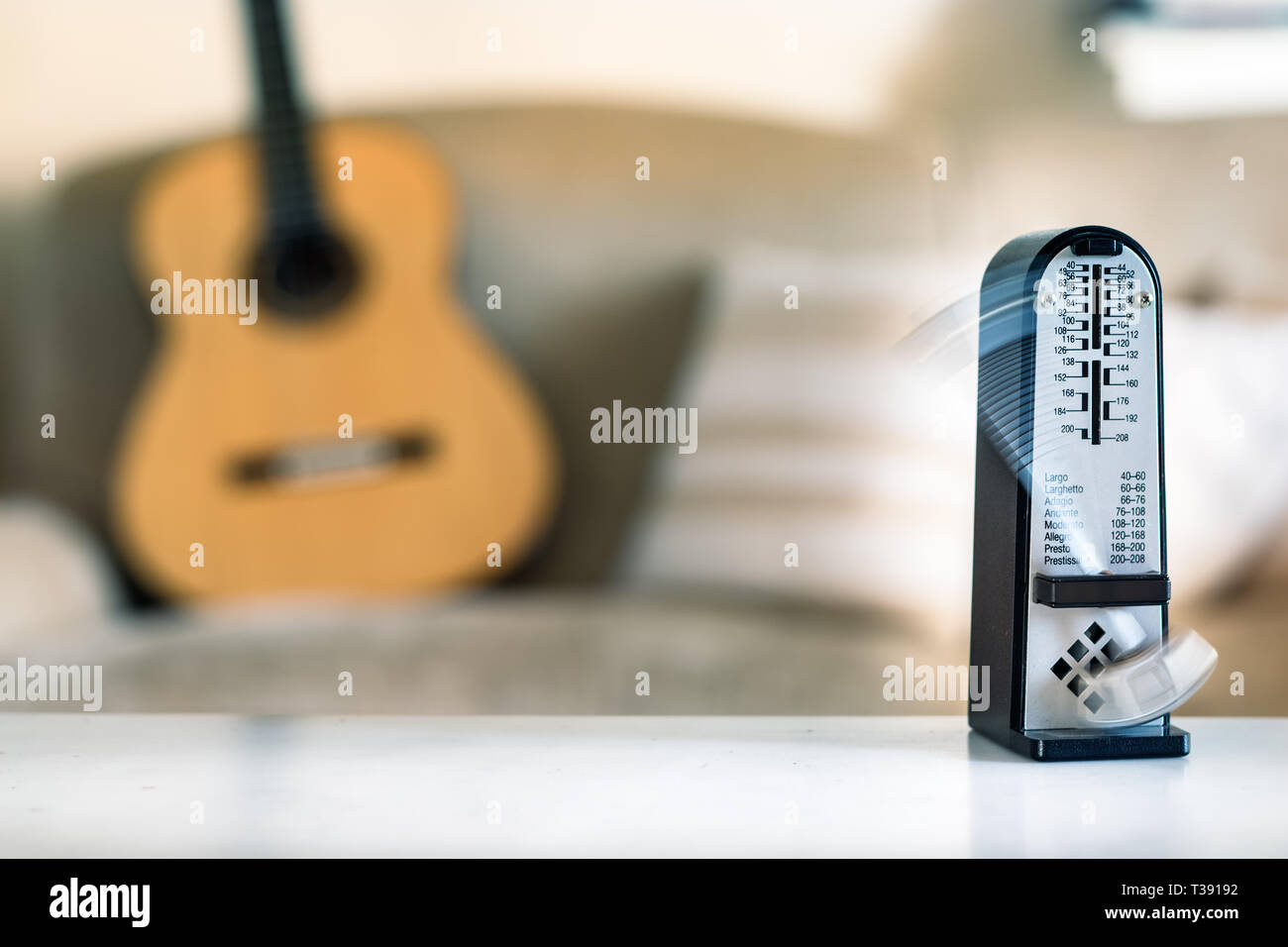 Mechanische Metronome in Bewegung, über eine hölzerne klassische Gitarre Hintergrund. Stockfoto