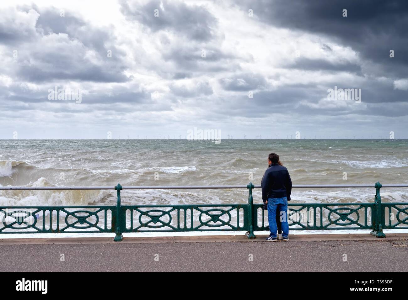 Junges Paar sehr nahe stehen, zusammen mit Blick aufs Meer in einer stürmischen Frühling auf der Strandpromenade Hoves entfernt East Sussex England Großbritannien Stockfoto