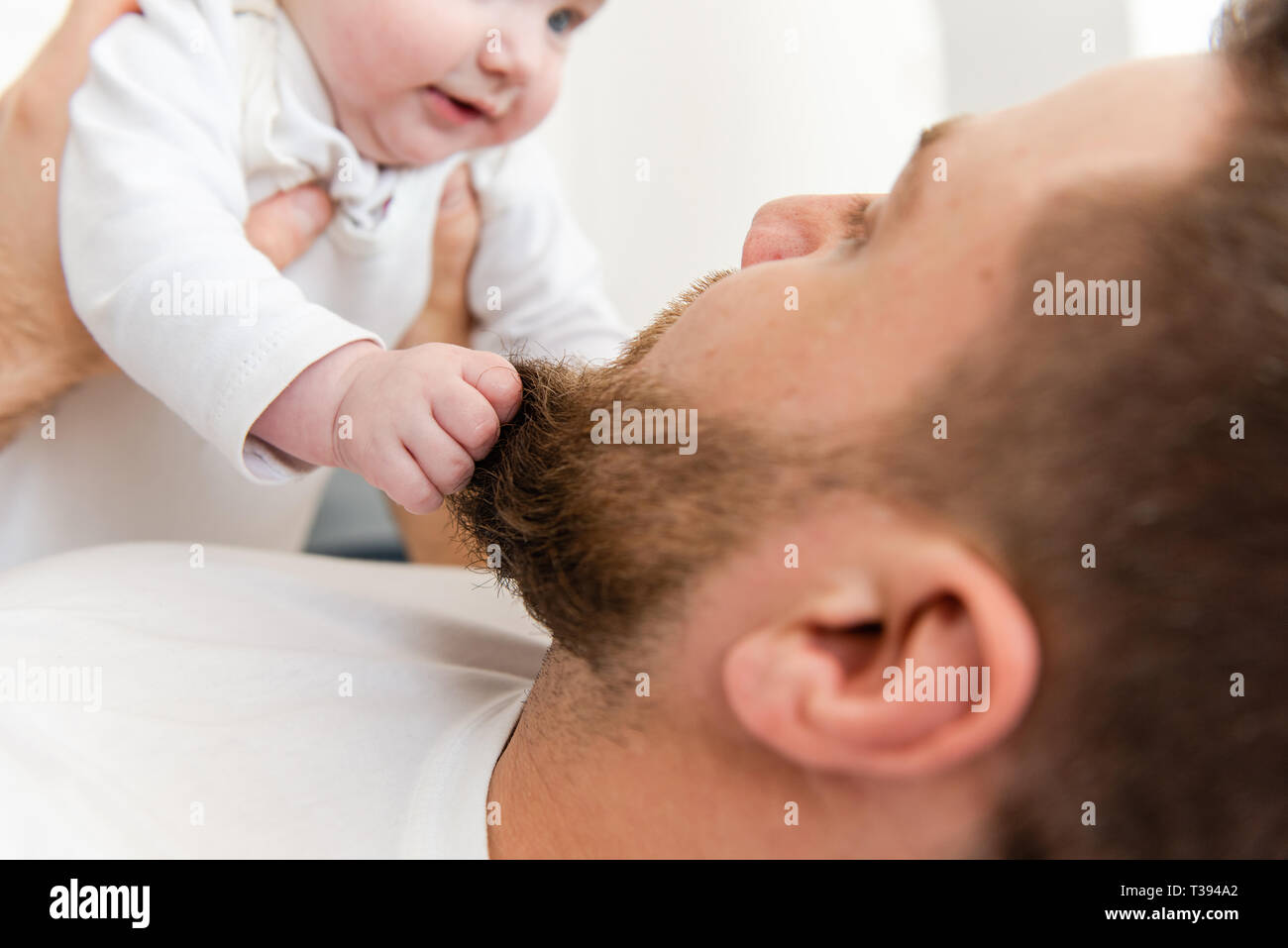 Baby Kind Hände greifen Bart des Mannes Stockfoto