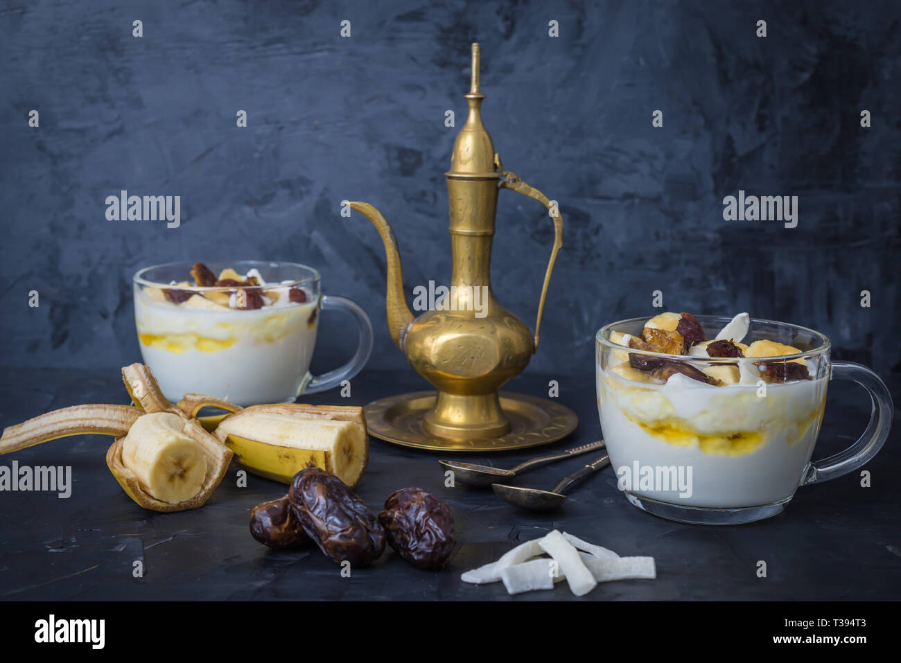 Iftar oder suhoor Snack in der Nähe der Termine mit Joghurt und Bananen mit Honig und Termine auf schwarzem Hintergrund, Ramadan Konzept Stockfoto