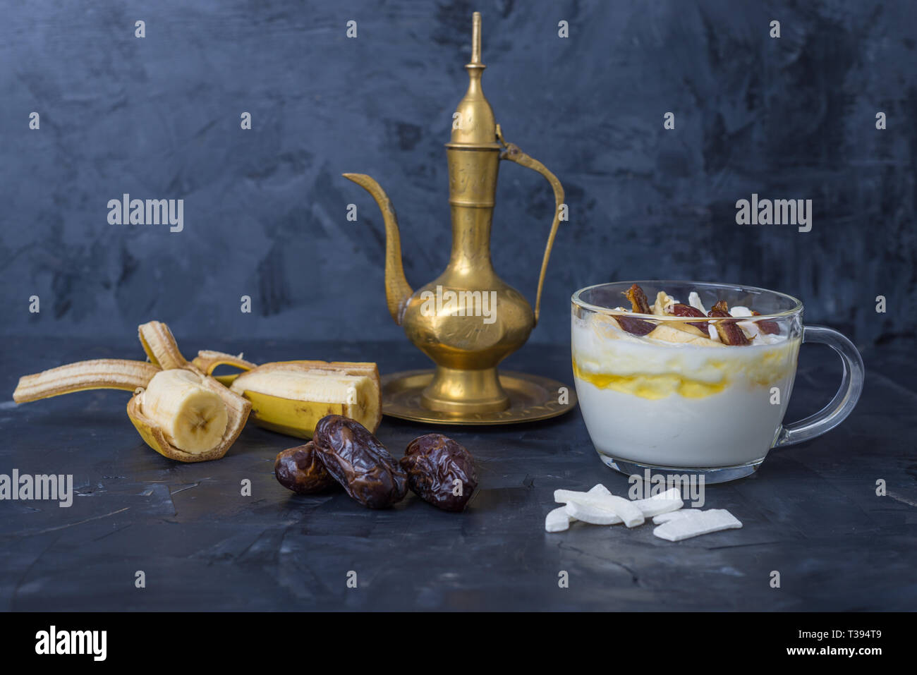 Iftar oder suhoor Snack in der Nähe der Termine mit Joghurt und Bananen mit Honig und Termine auf schwarzem Hintergrund, Ramadan Konzept Stockfoto