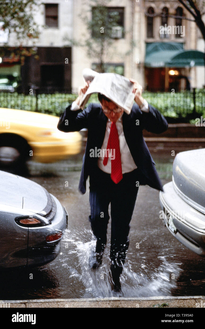 Geschäftsmann gefangen im Regen , NYC, USA 1990s Stockfoto