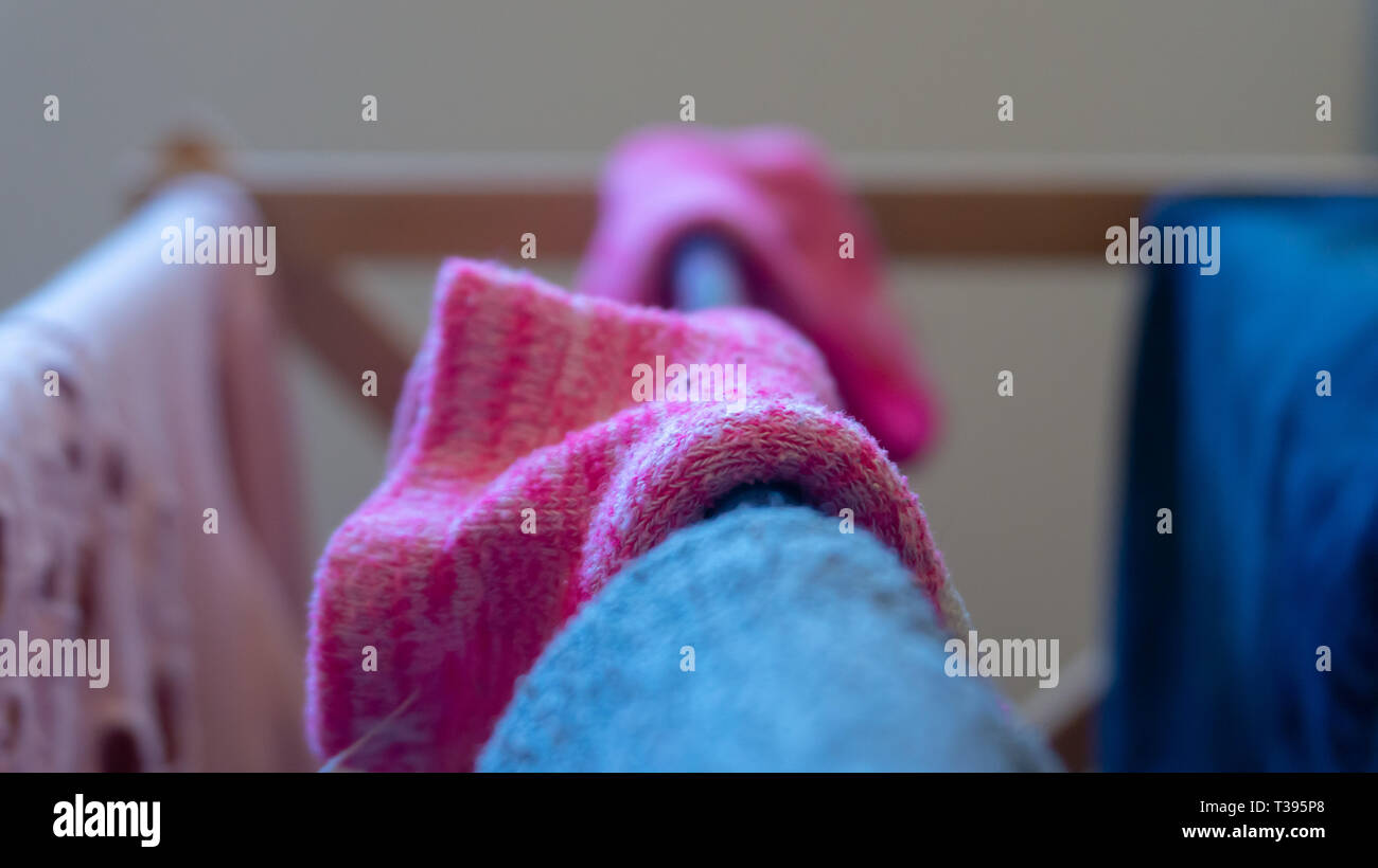 Makro Fotografie aus der Nähe Schuß von gewebten Rosa (magenta) Umschlagsocke trocknen auf einem Wäscheständer drinnen. Hintergrund unscharf, Zentrum selektive konzentrieren. Stockfoto