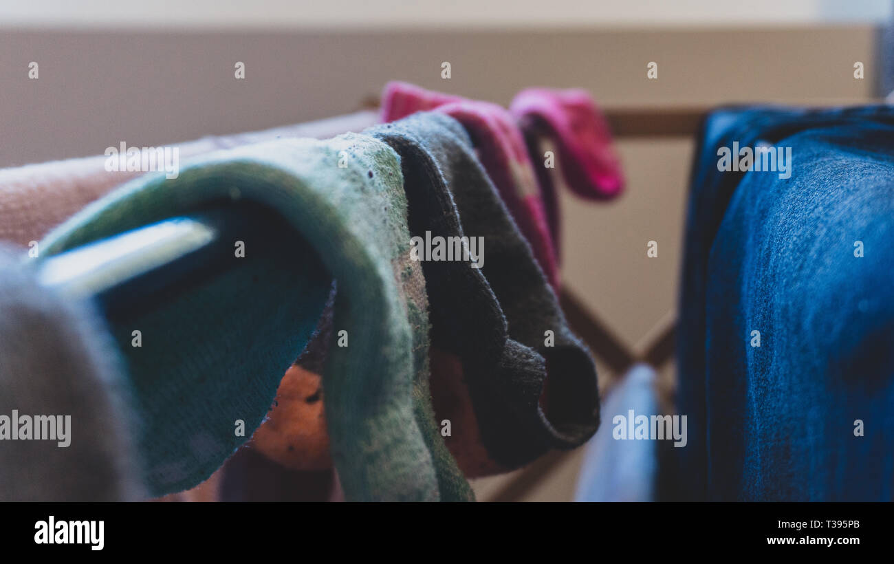 Dunkle, gefiltert, verblasst der ungleichen Paare Socken trocknen auf einem Wäscheständer, hängend Trocknen nach dem Waschen, mit Blue Jeans. Stockfoto