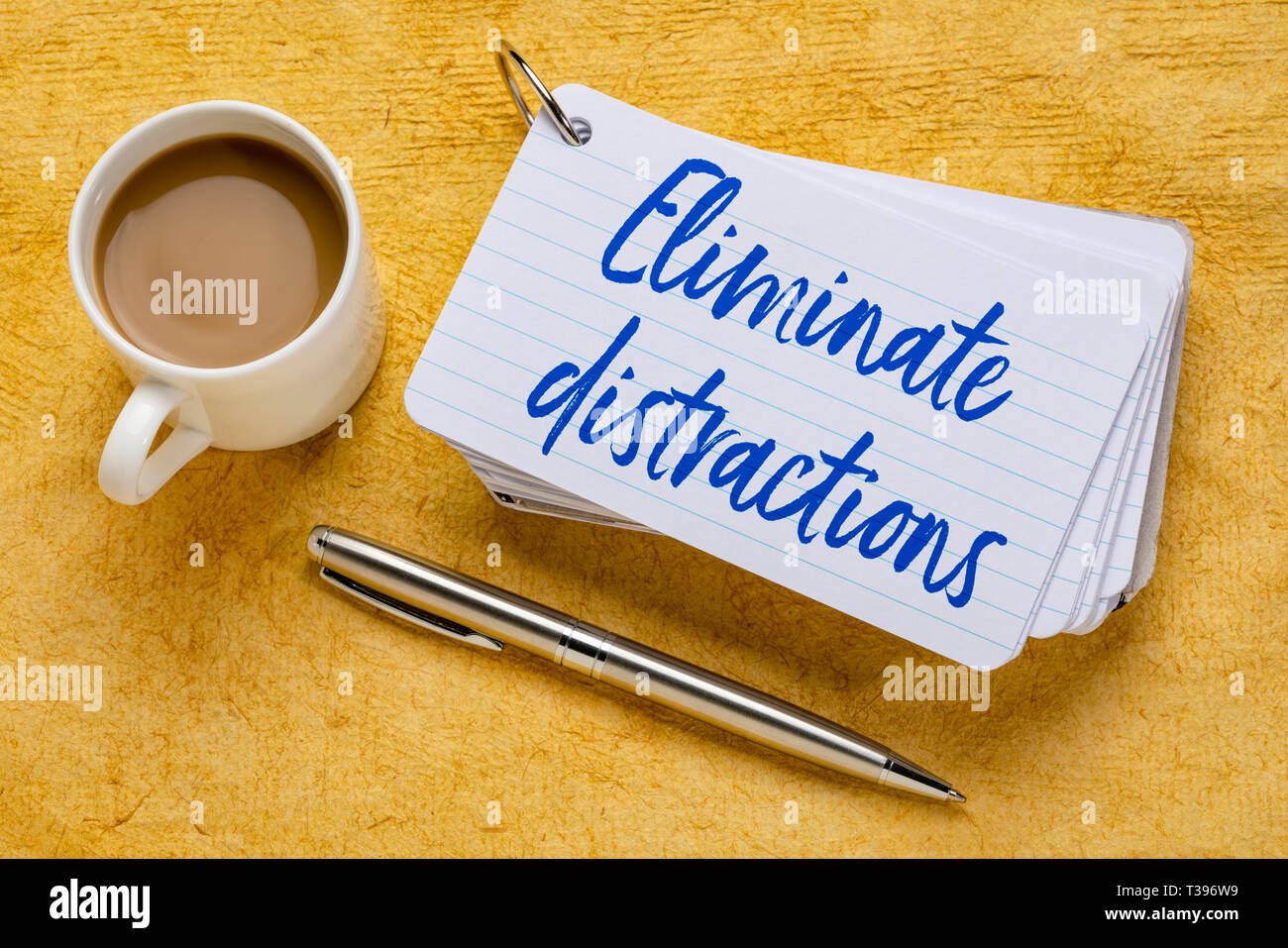 Ablenkungen - Handschrift auf einen Stapel Karteikarten mit einer Tasse Kaffee und einem Stift gegen Gelb strukturierte Papier eliminieren. Stockfoto