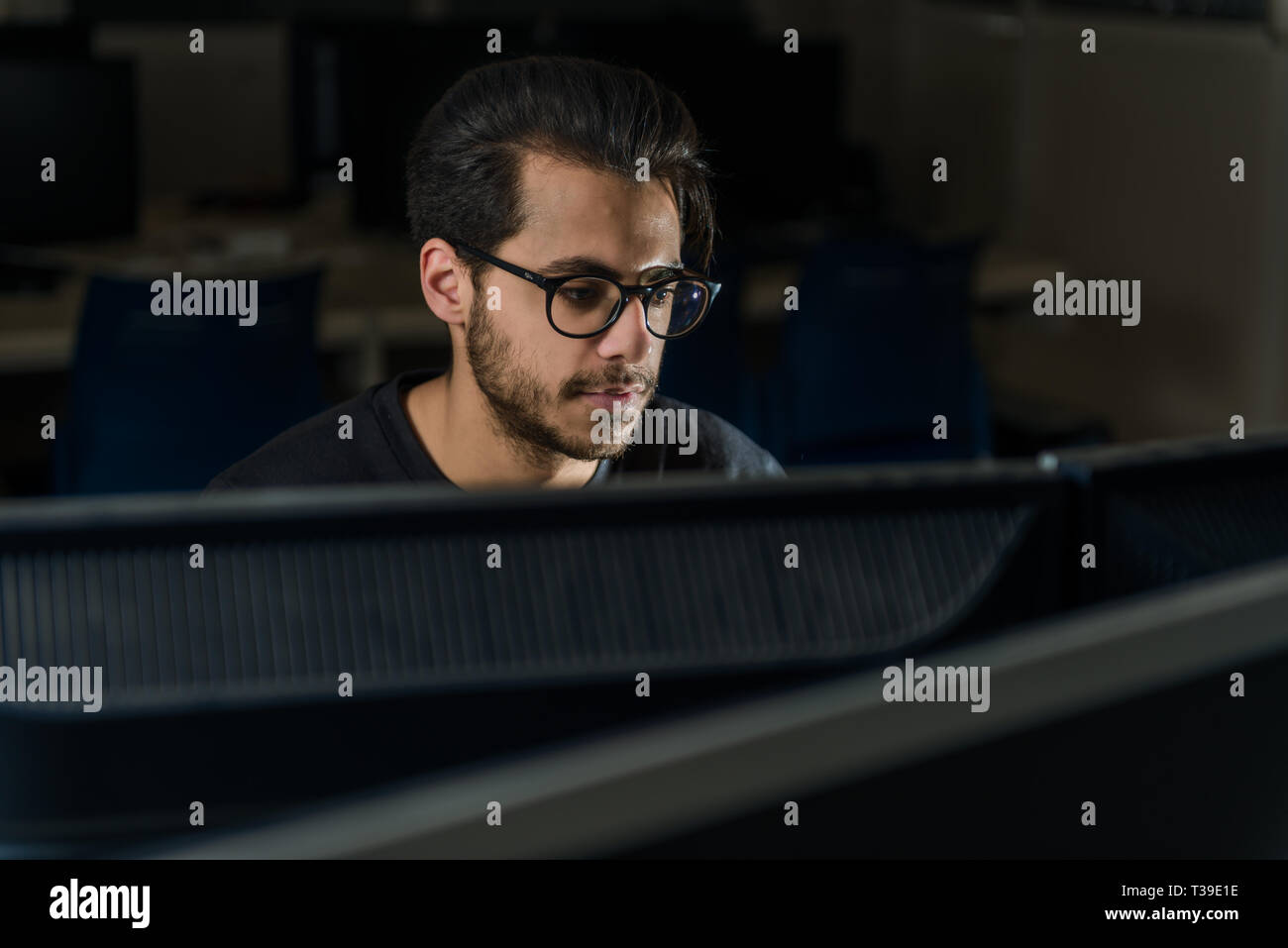 Blick über einen Bildschirm auf dem Gesicht eines jungen Informatik Schüler arbeiten mit dem Computer. Stockfoto
