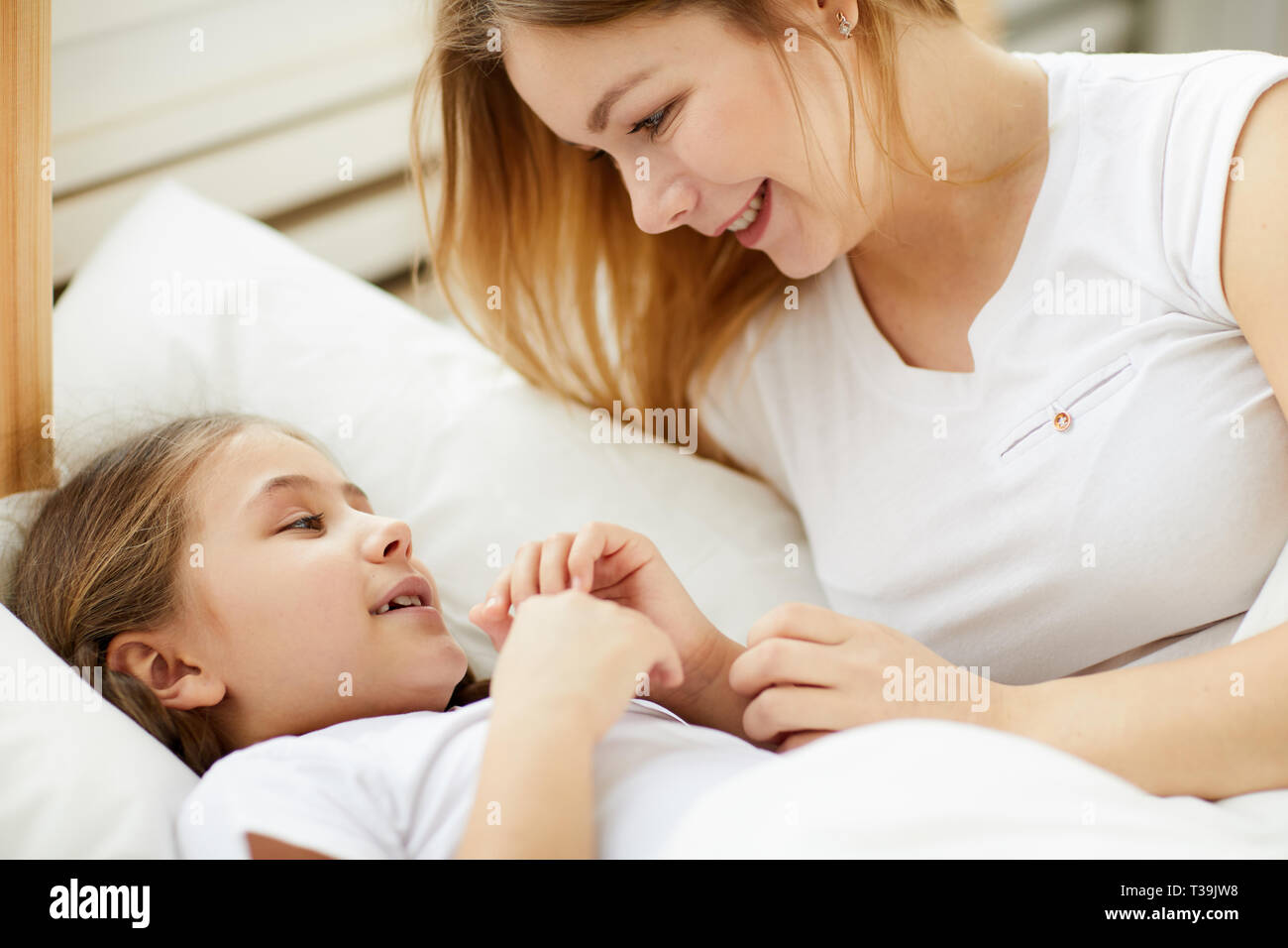 Fürsorgliche Mutter zur Tochter zu schlafen Stockfoto