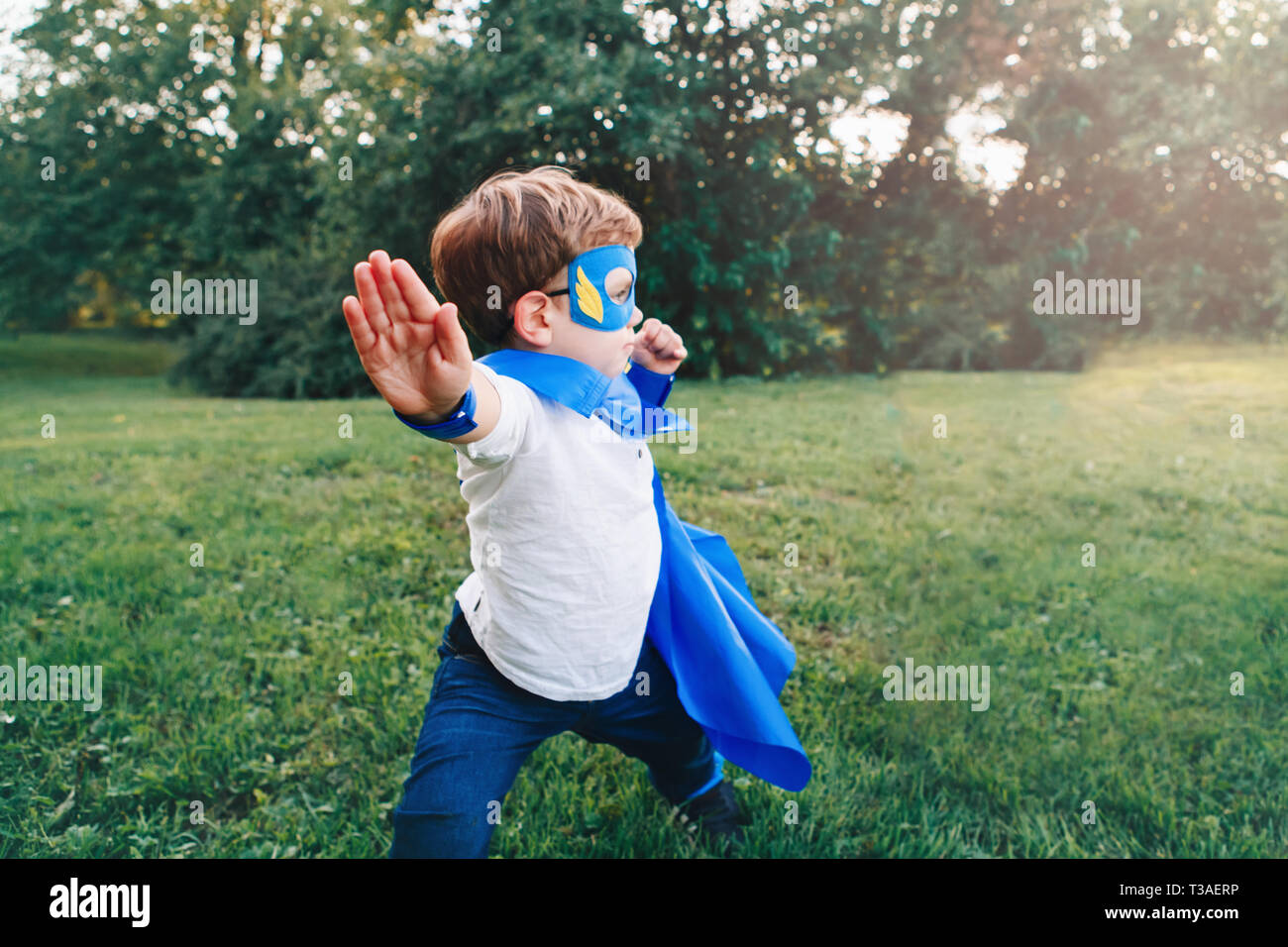 Cute adorable Vorschule kaukasischen Kind spielen Superheld im blauen Kostüm. Junge das Tragen der Maske und Cape Spaß draußen im Park. Gerne aktiv Chi Stockfoto