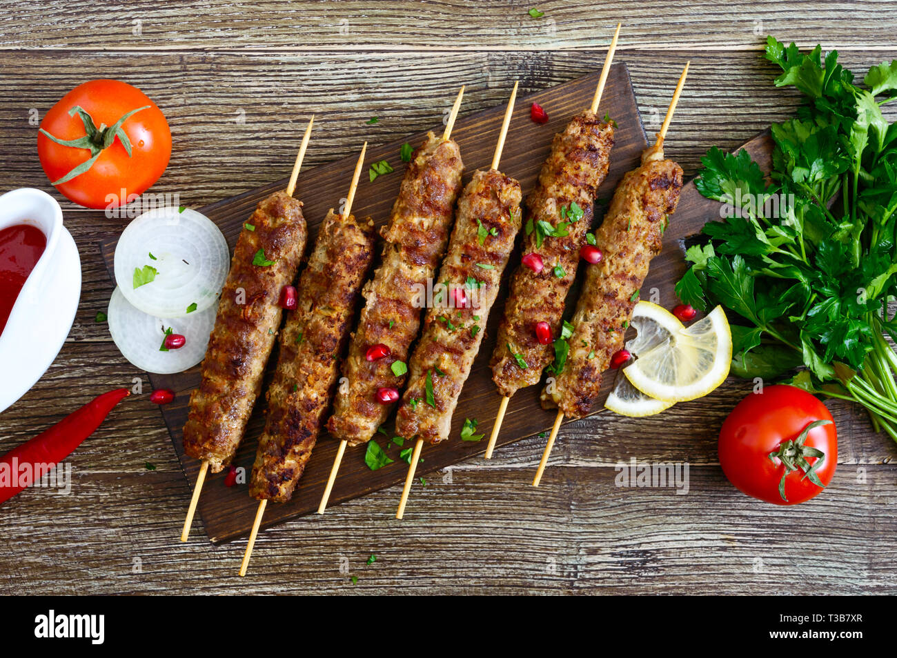Köstliche lula Kebab auf einem Holztisch. Gehacktes Fleisch auf Holzspieße, gegrillt. Östliche Küche. Ansicht von oben, flach. Stockfoto