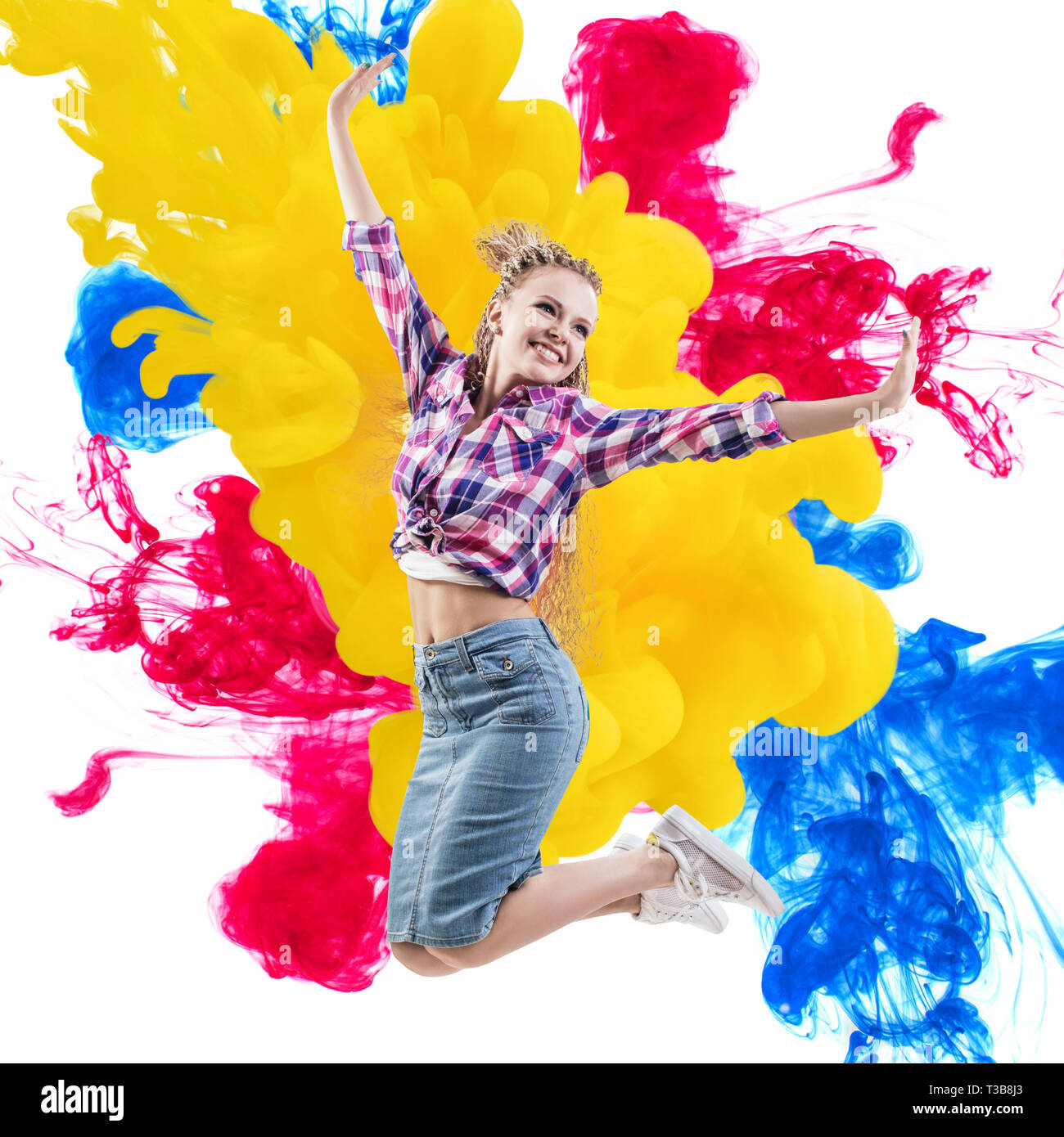 Glückliche Frau springt über Farben explosion Hintergrund. Stockfoto