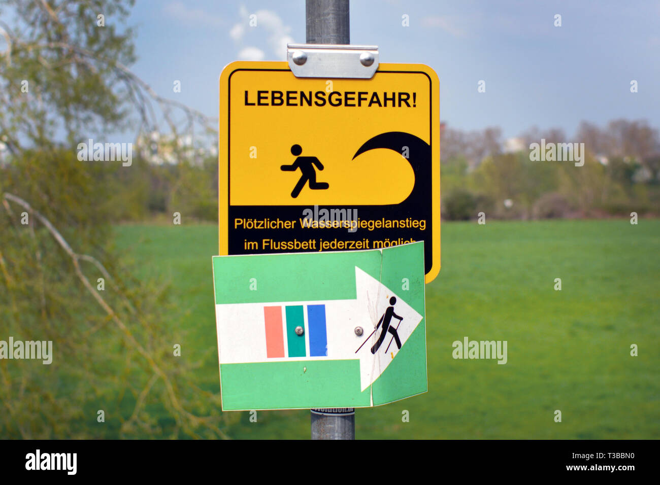 Warnung Schild 'Mortal Gefahr, plötzlichen Anstieg des Wasserstands in Riverbed möglich" in deutscher Sprache im Hochwasserschutz Wiese Stockfoto
