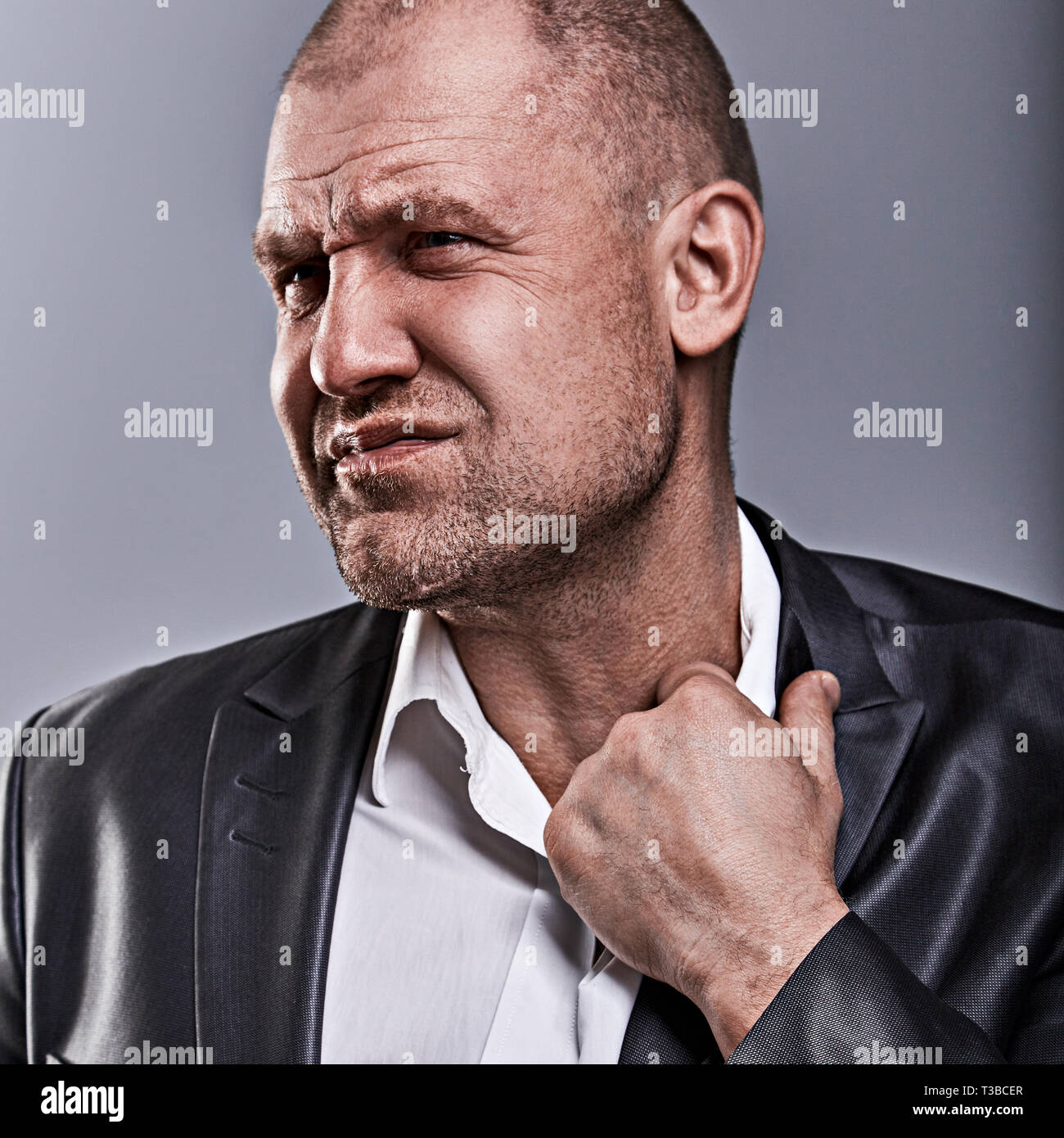 Unglücklich betonte Kahlen wütend Geschäftsmann ziehen der Hemdkragen mit sehr schlechten Emotionen in Bürosoftware auf Grau studio Hintergrund. Closeup Portrait Stockfoto
