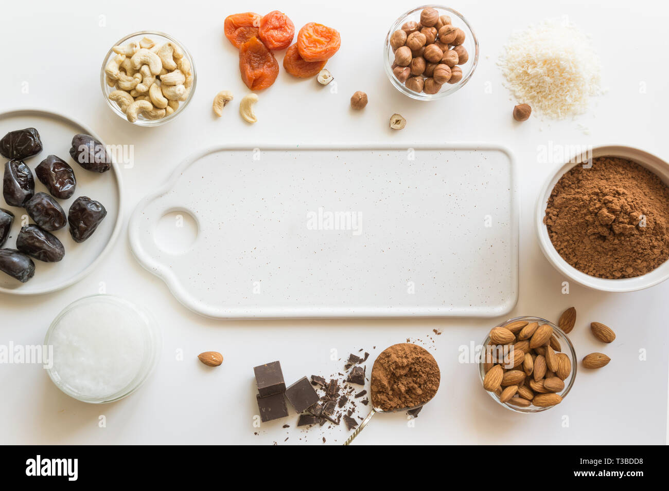 Nüsse und getrocknete Früchte für das Kochen Energie Termine Bälle. Cashew, Aprikosen, Kakaopulver und Muttern auf Weiß. Gesundes Essen für Vegetarier und Kinder. Stockfoto