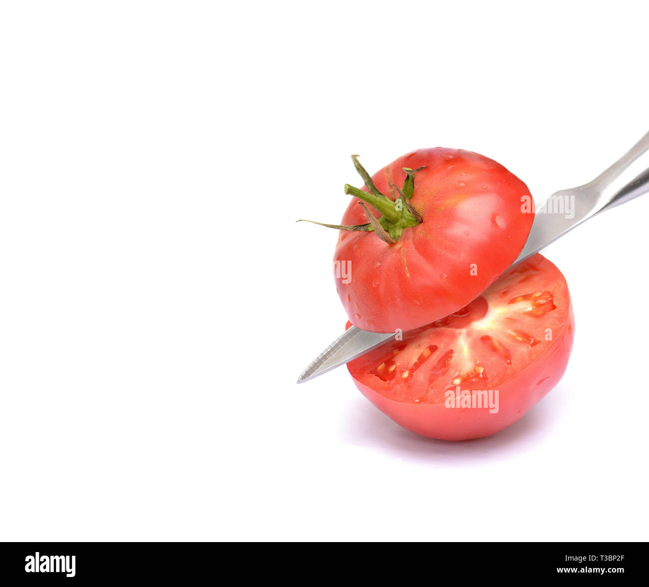 Schneiden Sie die Tomaten in der Hälfte mit einem Messer auf einem weißen Hintergrund isoliert. Stockfoto