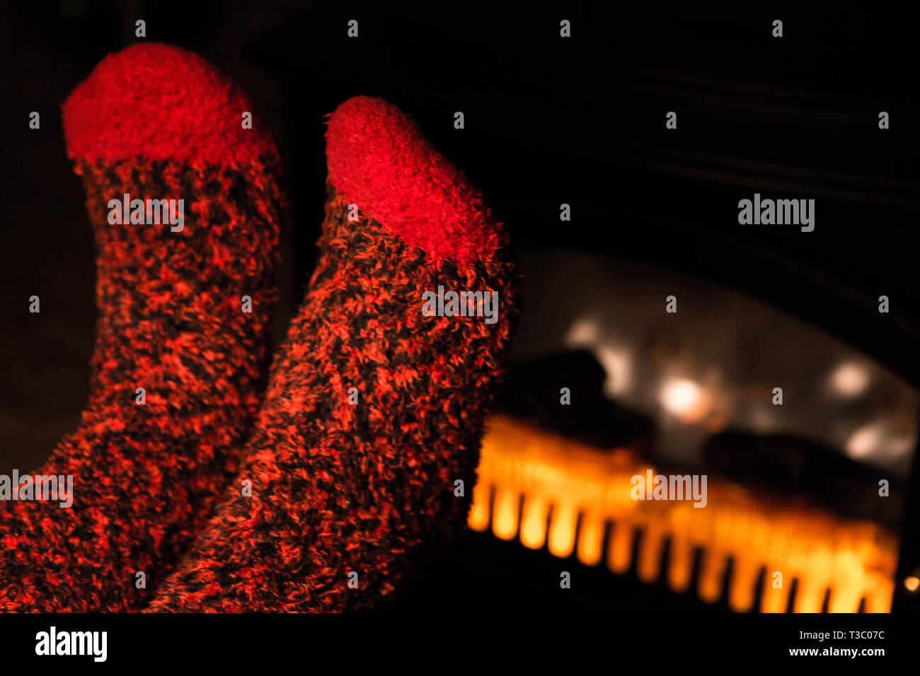 Wärmende Füße in Wollsocken mit Kamin Stockfoto