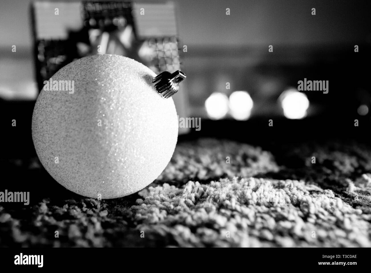 Sparkly White Christmas Ball mit Geschenk im Hintergrund Schwarz und Weiß Low Key Stockfoto