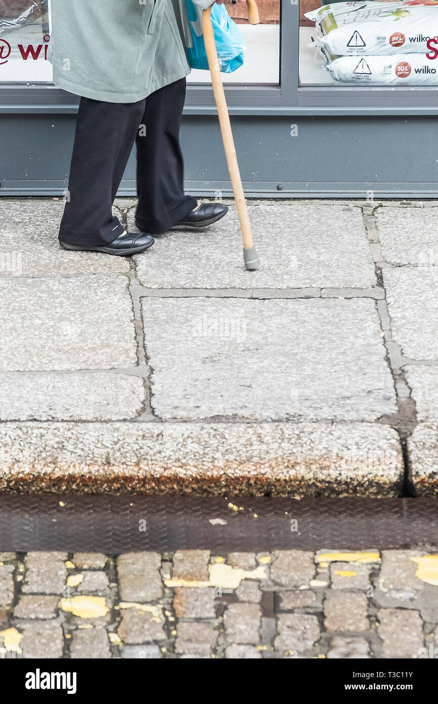 Eine ältere Dame zu Fuß mit der Hilfe von einem Stock. Stockfoto