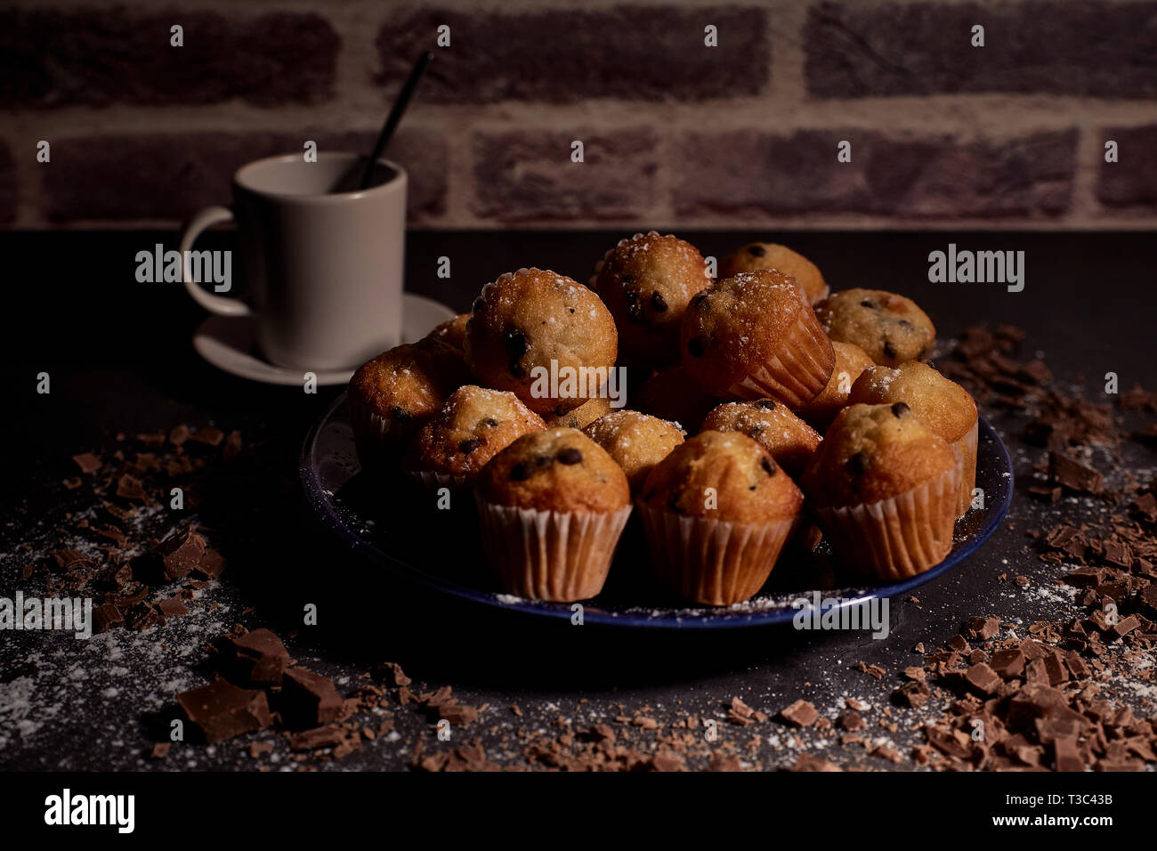 Gruppe von Muffins mit Schokolade auf blauem Teller weiter zu einer Tasse Milch Stockfoto