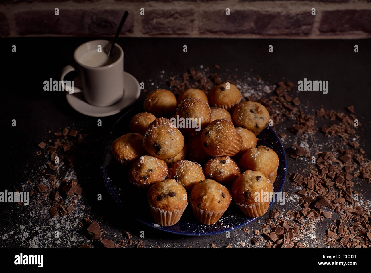 Gruppe von Muffins mit Schokolade auf blauem Teller weiter zu einer Tasse Milch Stockfoto