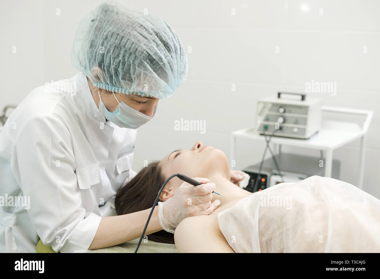 Medizinische Behandlung Entfernung von muttermal vom Hals des weiblichen Patienten. Weibliche Dermatologe Chirurg mit einem professionellen Elektrokauter für das Entfernen der Maulwurf. Stockfoto