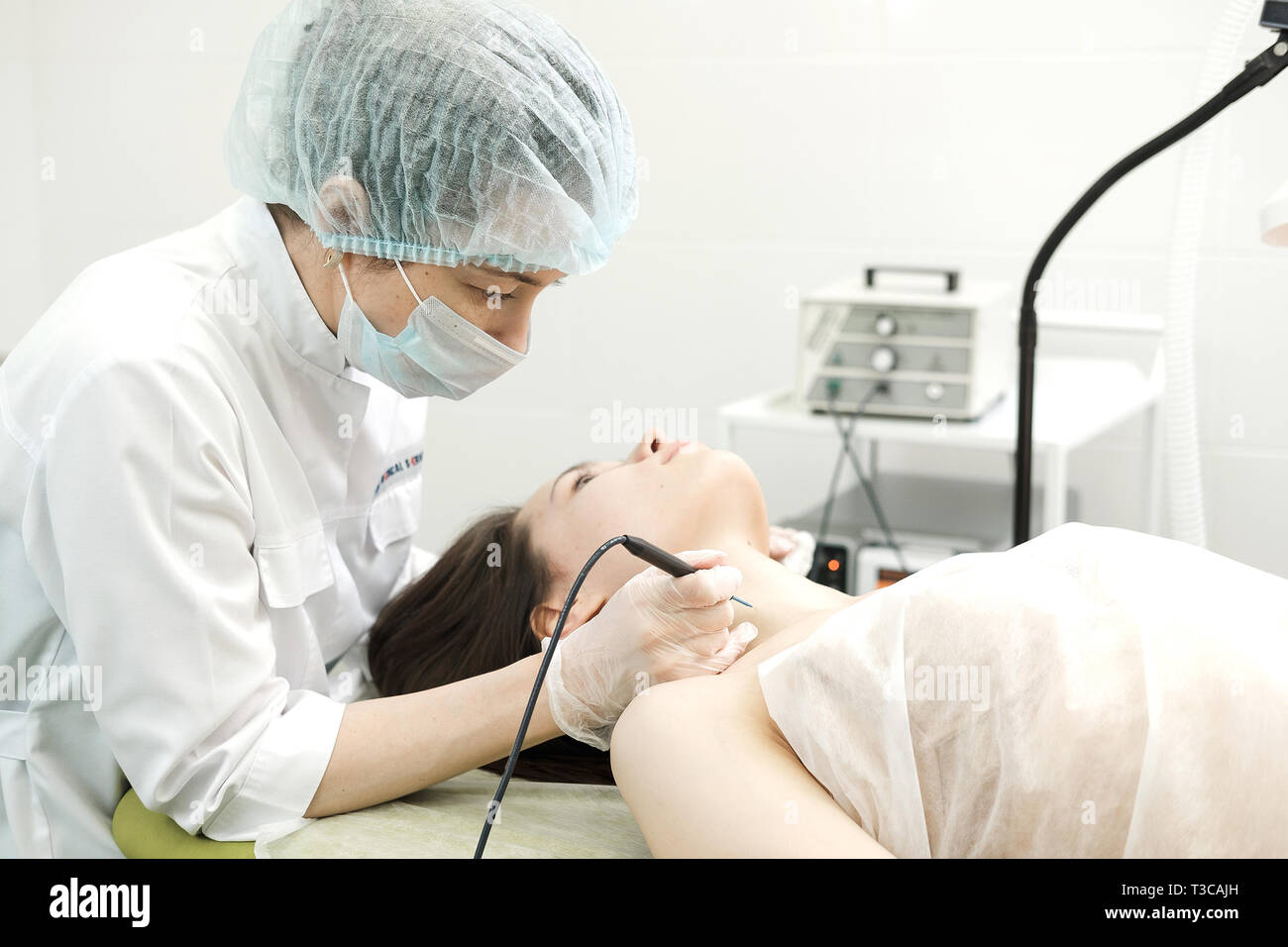 Medizinische Behandlung Entfernung von muttermal vom Hals des weiblichen Patienten. Weibliche Dermatologe Chirurg mit einem professionellen Elektrokauter für das Entfernen der Maulwurf. Stockfoto