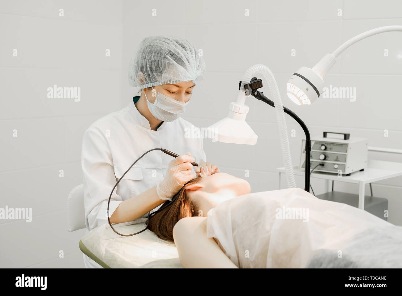 Medizinische Behandlung Entfernung von muttermal von Gesicht des weiblichen Patienten. Weibliche Dermatologe Chirurg mit einem professionellen Elektrokauter für das Entfernen der Maulwurf. Stockfoto